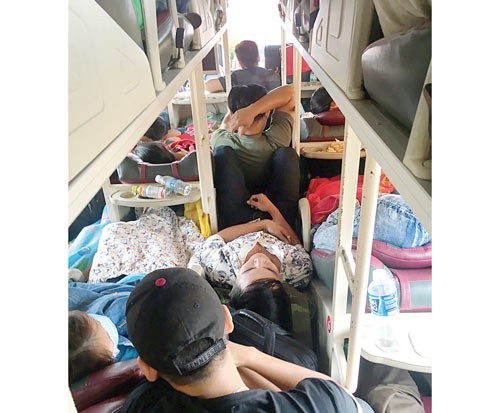 Many passengers seat on the floor board of a coach from Binh Thuan province to HCMC on February 1 (Photo: SGGP)